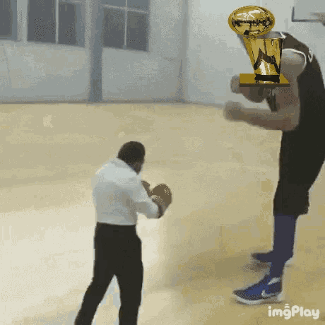 a basketball player is holding a trophy over his head while a man stands behind him .