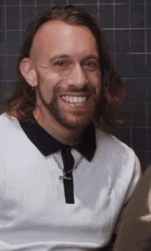 a man with long hair and a beard wearing a white shirt