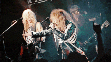 a man singing into a microphone with the word guns n ' roses on his shirt