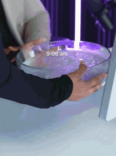 a person is holding a bowl of water with 9:06 am written on it