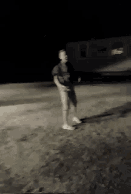 a man in a black shirt and white shoes is dancing in the dark .