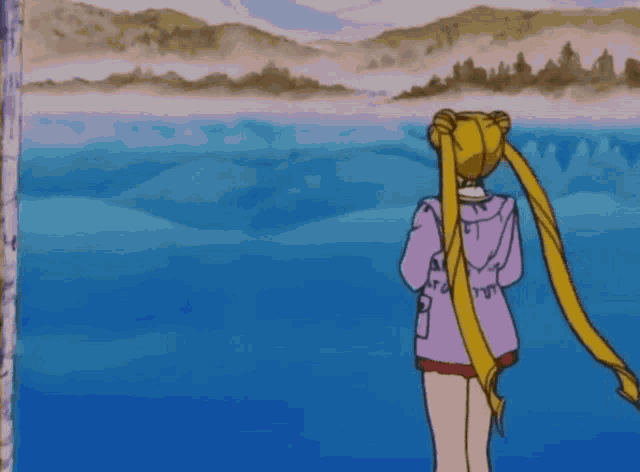 a girl with long blonde hair is standing in front of a body of water with mountains in the background