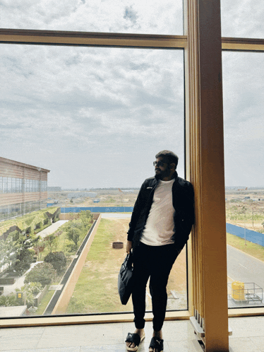 a man standing in front of a large window looking out