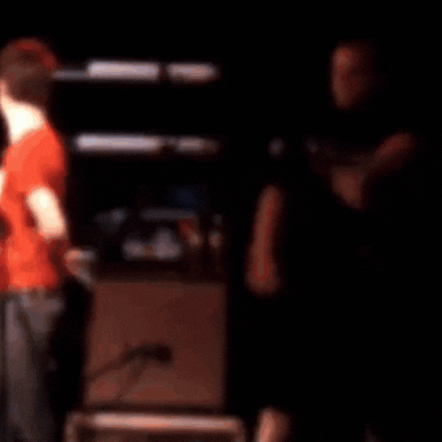 a man in a red shirt is talking to another man in a black shirt