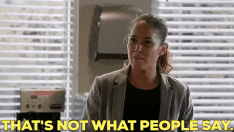 a woman is standing in front of a window with blinds and says `` that 's not what people say '' .