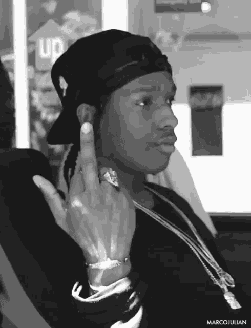 a black and white photo of a man wearing a hat and giving the middle finger by marcojulian