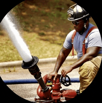 a fireman wearing a helmet and goggles is kneeling down and using a fire hose