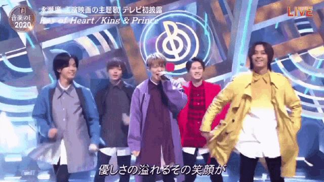 a group of young men are dancing on a stage with a sign that says live in the background