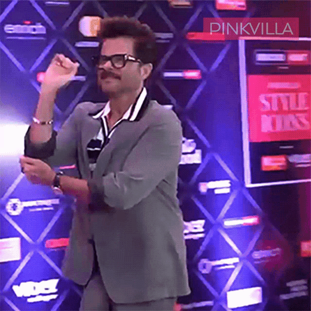 a man in a suit is dancing in front of a pinkvilla sign