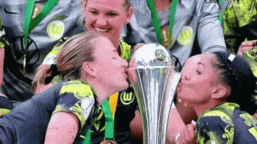 a group of female soccer players kissing a trophy