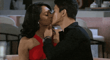 a man and a woman are kissing while sitting at a table