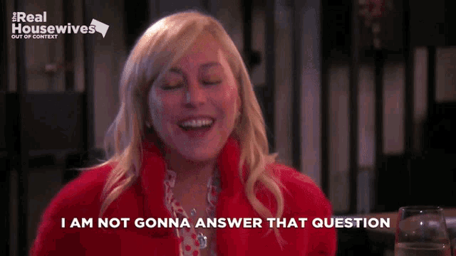 a woman in a red coat is laughing and says i am not gonna answer that question