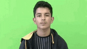 a young man in a black jacket is standing in front of a green screen .