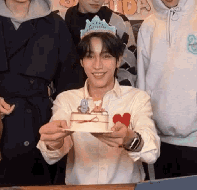 a man wearing a happy birthday crown is holding a cake in his hands