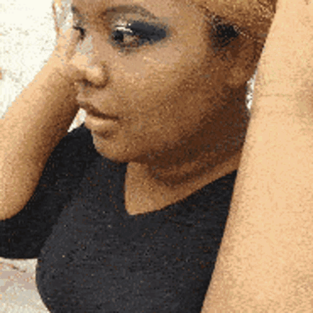 a woman in a black shirt holds her hands to her face