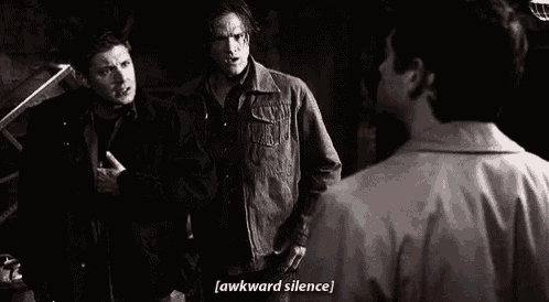 a group of men are standing next to each other in a dark room and one of them is talking to another man .