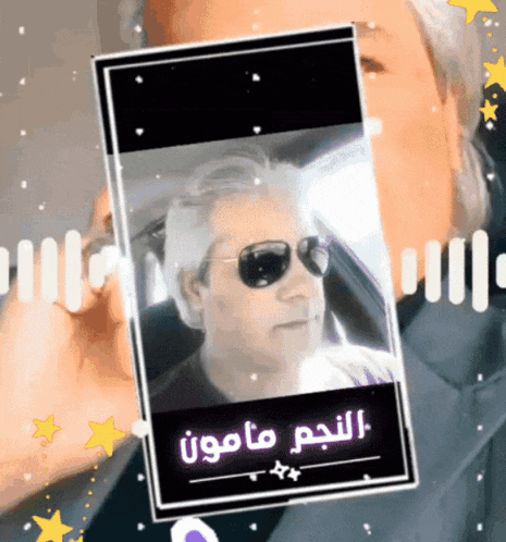 a man wearing sunglasses is behind a phone screen with arabic writing on it