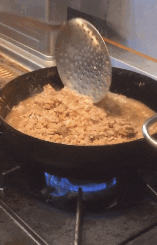 a strainer is being used to stir food in a pan on a stove