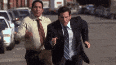 two men in suits and ties running down a street