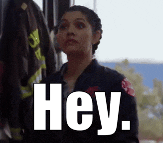 a woman in a firefighter 's uniform is standing next to a fire truck and says hey .