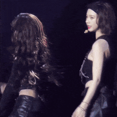 two women are dancing on a stage and one is giving a thumbs up sign