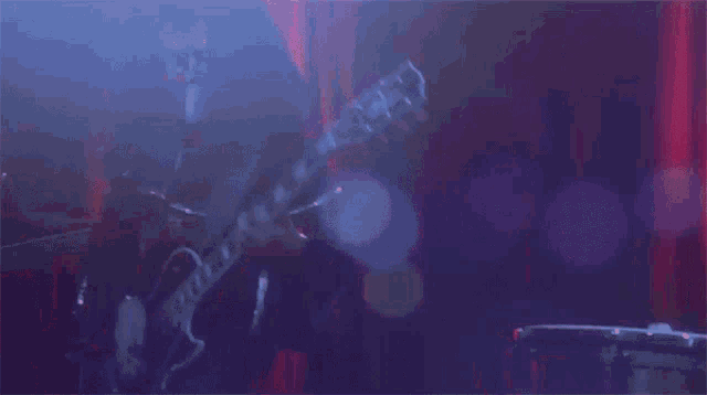 a man is playing a guitar on stage in a dark room