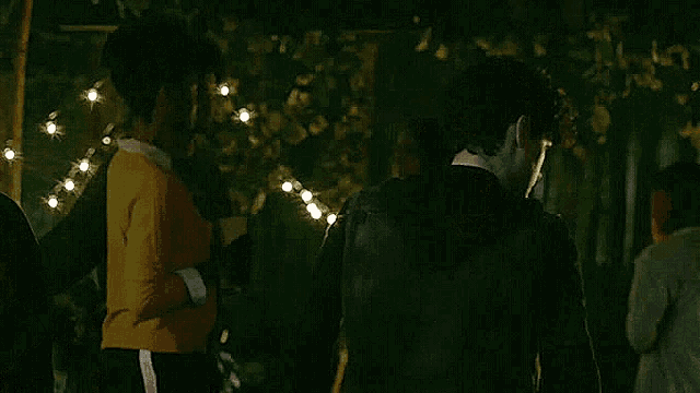 a group of people are standing in a dark room with christmas lights .