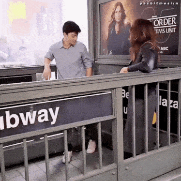 a man and a woman standing in front of a subway sign
