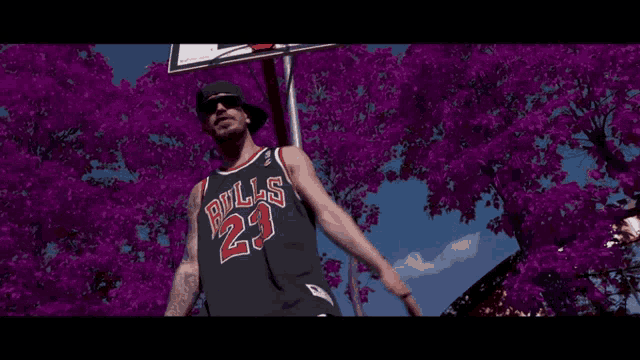 a man wearing a bulls jersey stands in front of purple flowers