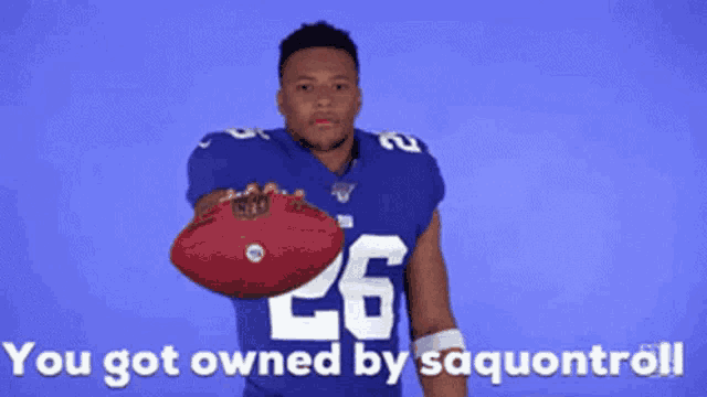 a football player with the number 26 on his jersey holds a football in his hand