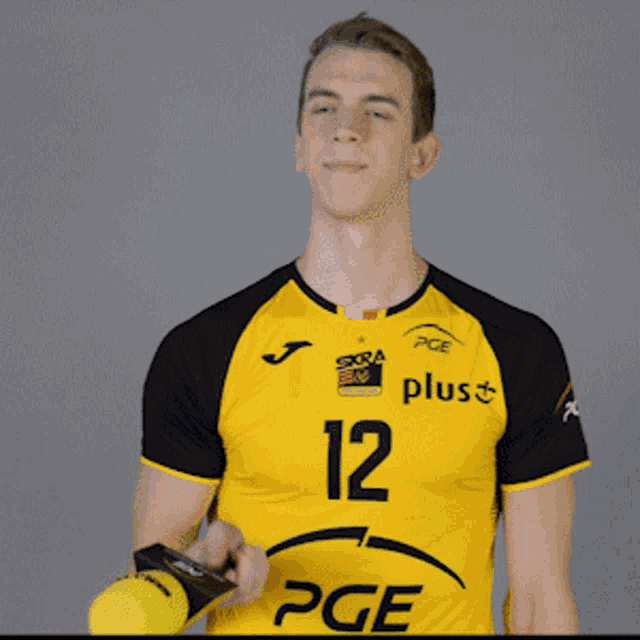a man wearing a yellow pge jersey holds a microphone