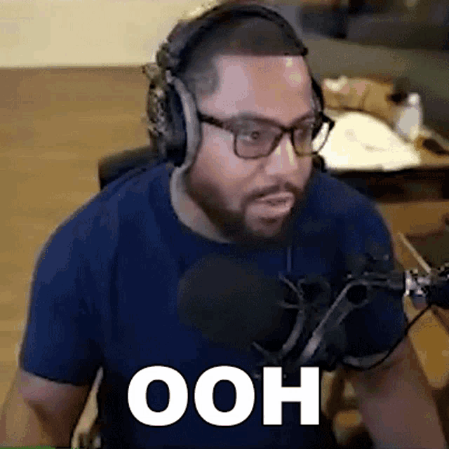 a man wearing headphones and glasses is sitting in front of a microphone and says ooh .