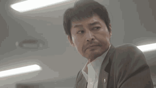 a man in a suit and white shirt has a badge on his chest