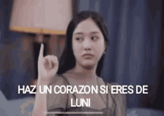 a woman is pointing up with the words haz un corazon si eres de luni written below her