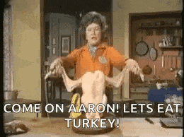 a woman is holding a turkey on a table in a kitchen .