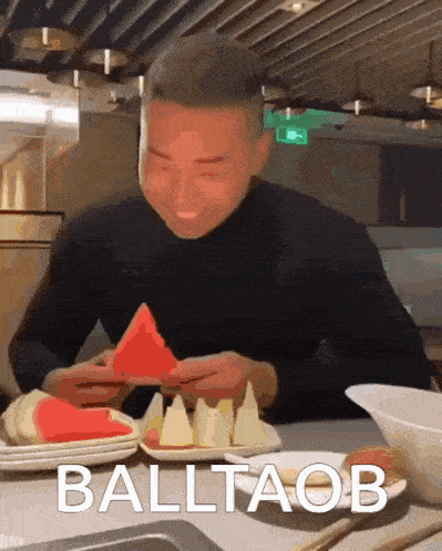 a man is eating a slice of watermelon with the word balltaob written on the bottom