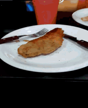a white plate with a piece of food on it with a fork and knife