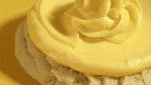 a cookie with yellow frosting is on a yellow surface