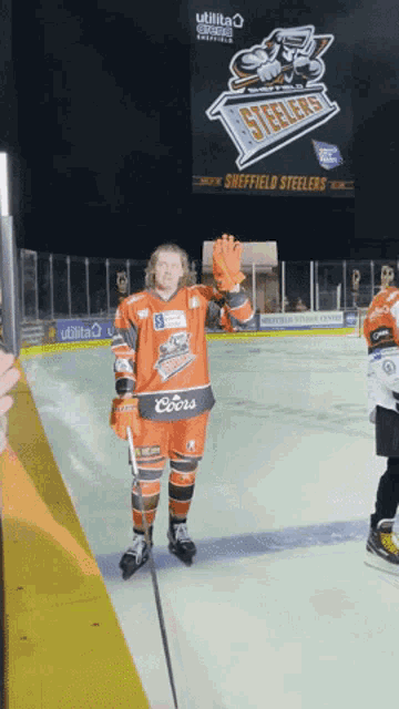 a hockey player wearing an orange jersey with coors on the front