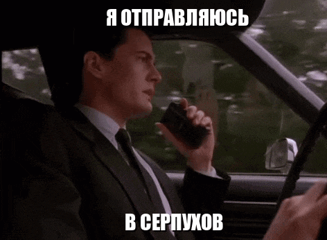 a man in a suit and tie is talking on a walkie talkie in his car