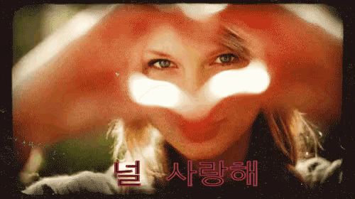 a woman making a heart shape with her hands in front of her eyes
