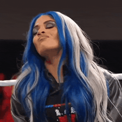 a woman with blue and white hair is standing in a ring .