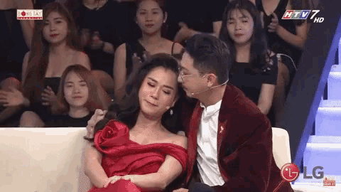 a man kisses a woman 's forehead while sitting on a couch in front of a lg logo