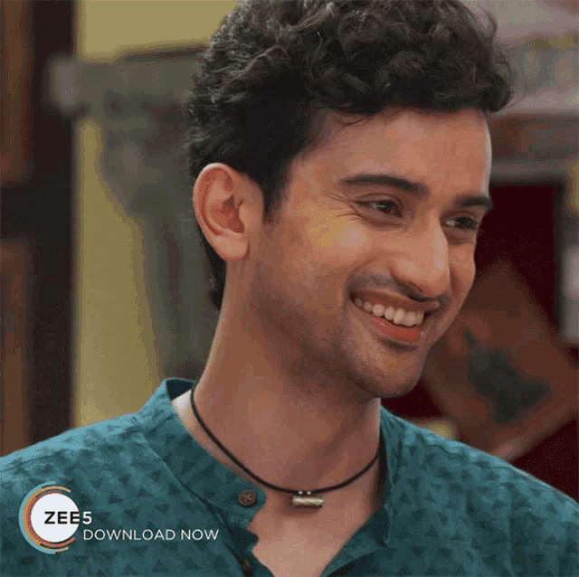 a man wearing a green shirt and a necklace is smiling with a zees download now advertisement in the background