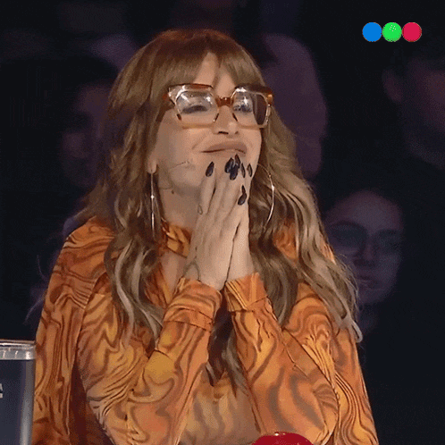 a woman wearing glasses and an orange shirt covering her mouth