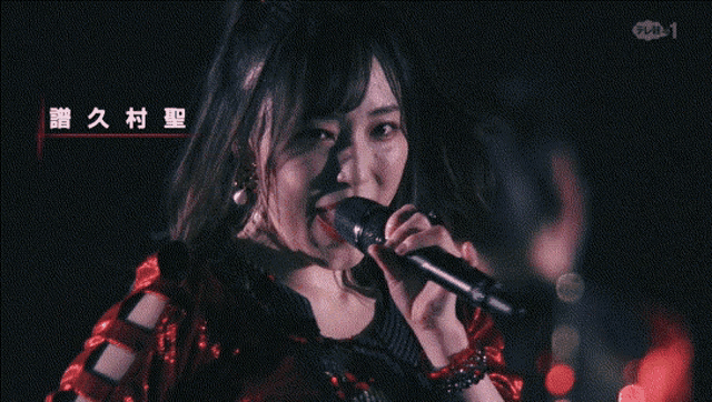 a woman singing into a microphone with chinese writing on the bottom right