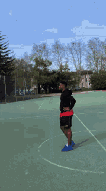 a man standing on a basketball court with his hands on his hips ..