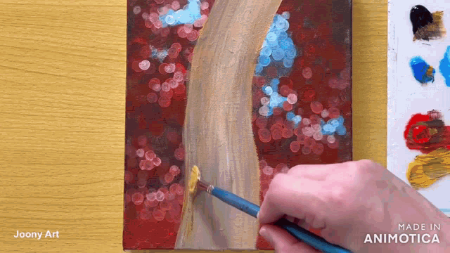 a person is painting a tree with a brush and the words made in animatica are on the bottom
