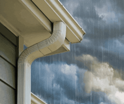 a gutter on the side of a house with a cloudy sky behind it