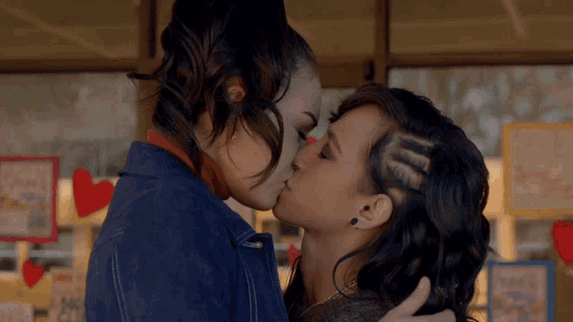 a couple of women kissing in front of a sign that says ' love '